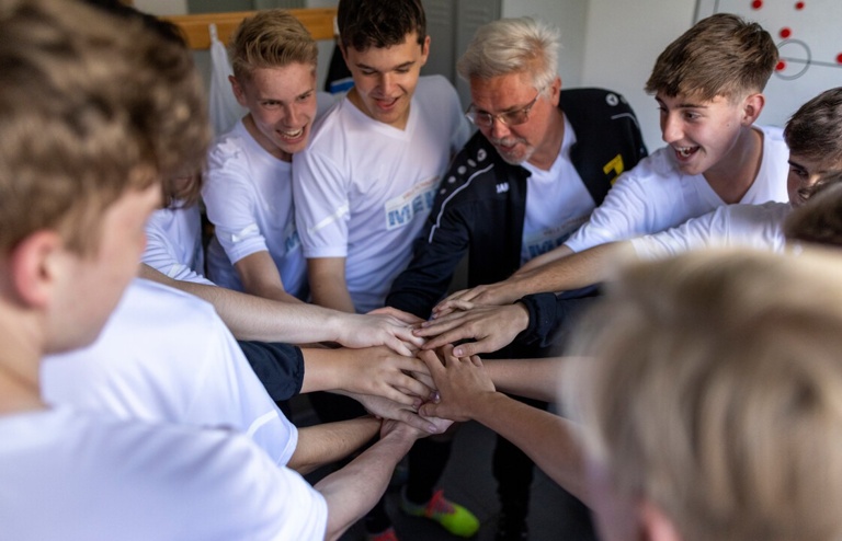 Das Bild zeigt ein motiviertes Team, das die Hände in der Mitte zusammenlegt – ein Symbol für Gemeinschaft, Zusammenhalt und erfolgreiches Crowdfunding.